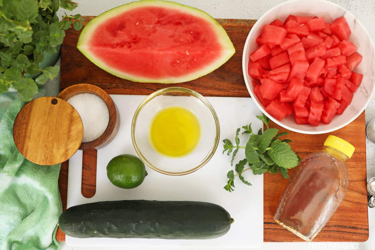 Watermelon feta salad ingredients: watermelon, cucumber, fresh mint leaves, honey, salt, olive oil, and a lime.