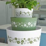Three plant pots that look like vintage pyrex bowls with a white and green daisy pattern.
