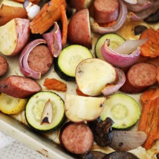 Corner view of a pan of roasted kielbasa and veggies.