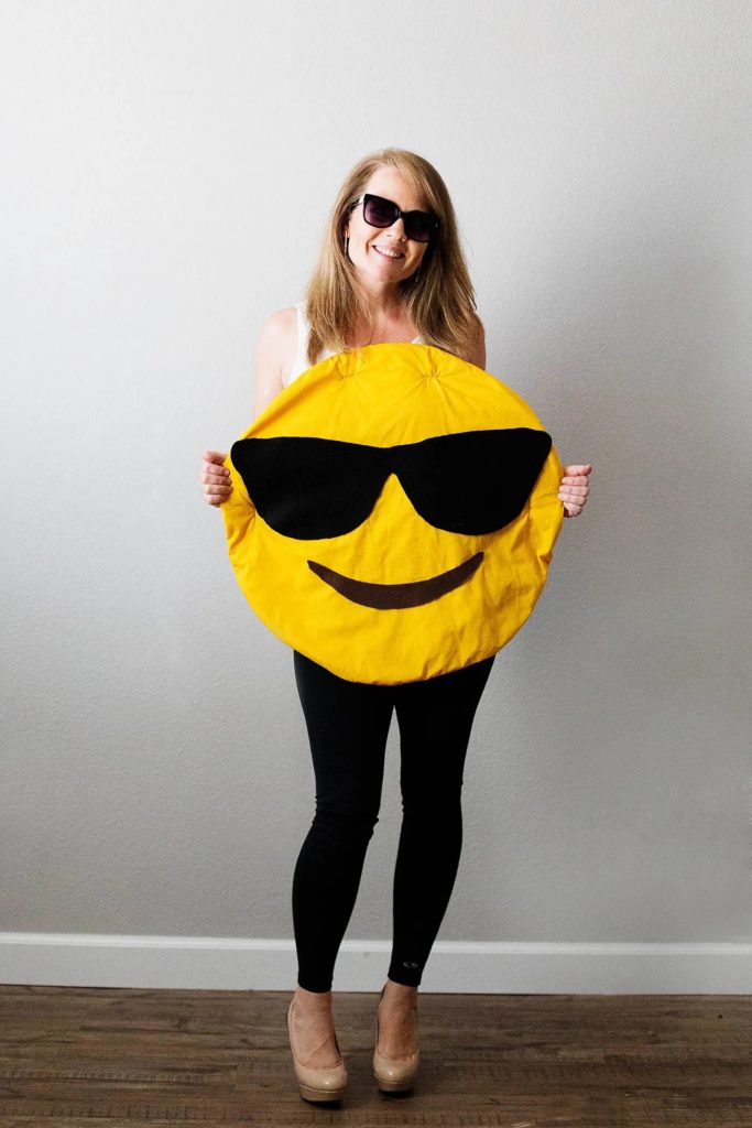Emoji costume for Halloween smiling emoji wearing sunglasses on a woman.
