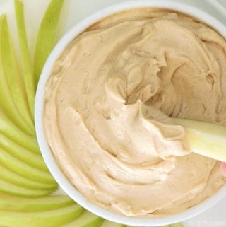 creamy apple dip in a white bowl with granny smith apple slices surrounding it.