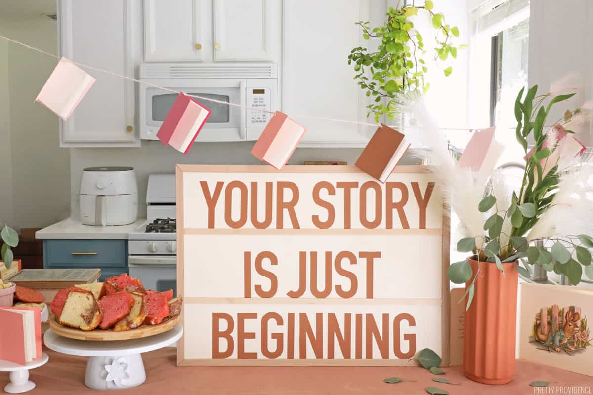 DIY Baby Shower Sign that says 'Your Story is Just Beginning' with book baby shower decorations.