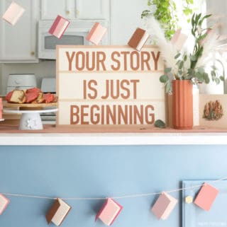 A counter with baby shower decorations - a banner made of mini books and a sign that says 'your story is just beginning.'