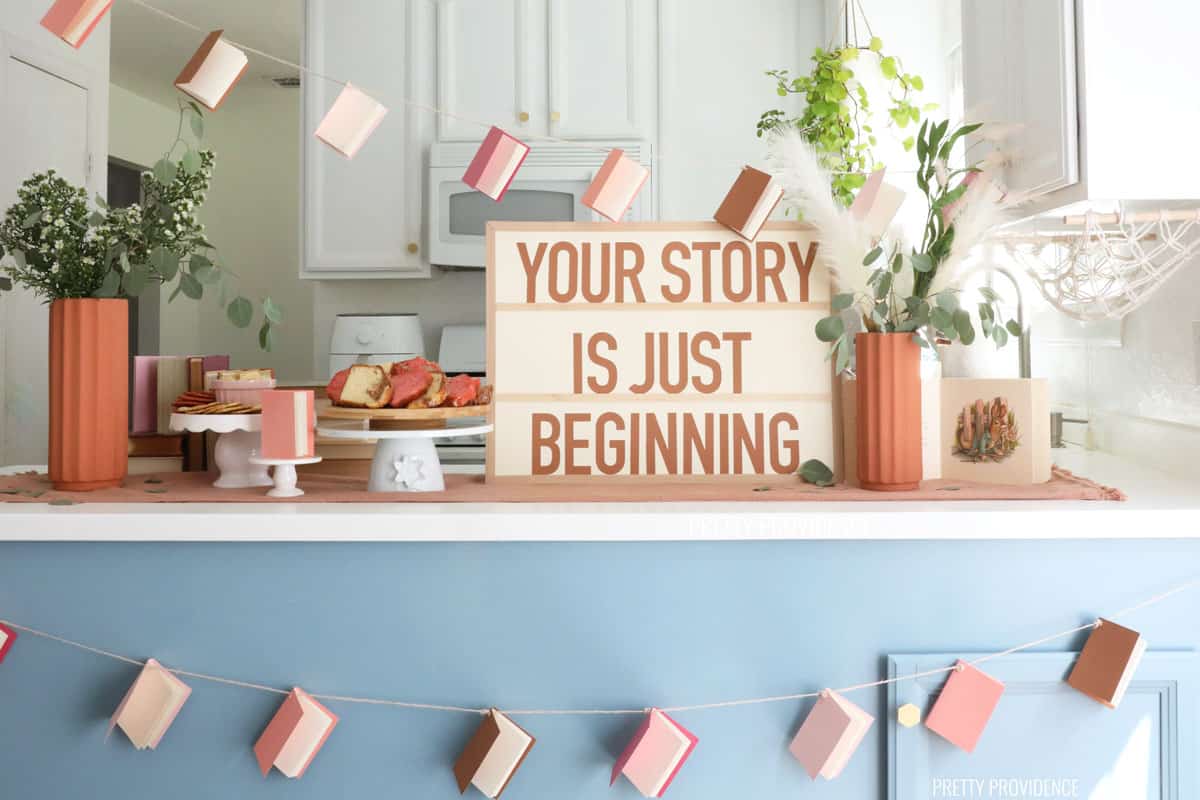 A counter with baby shower decorations - a banner made of mini books and a sign that says 'your story is just beginning.' 