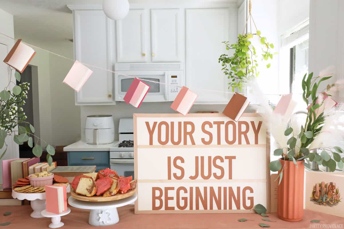 A counter with baby shower decorations - a banner made of mini books and a sign that says 'your story is just beginning.' 
