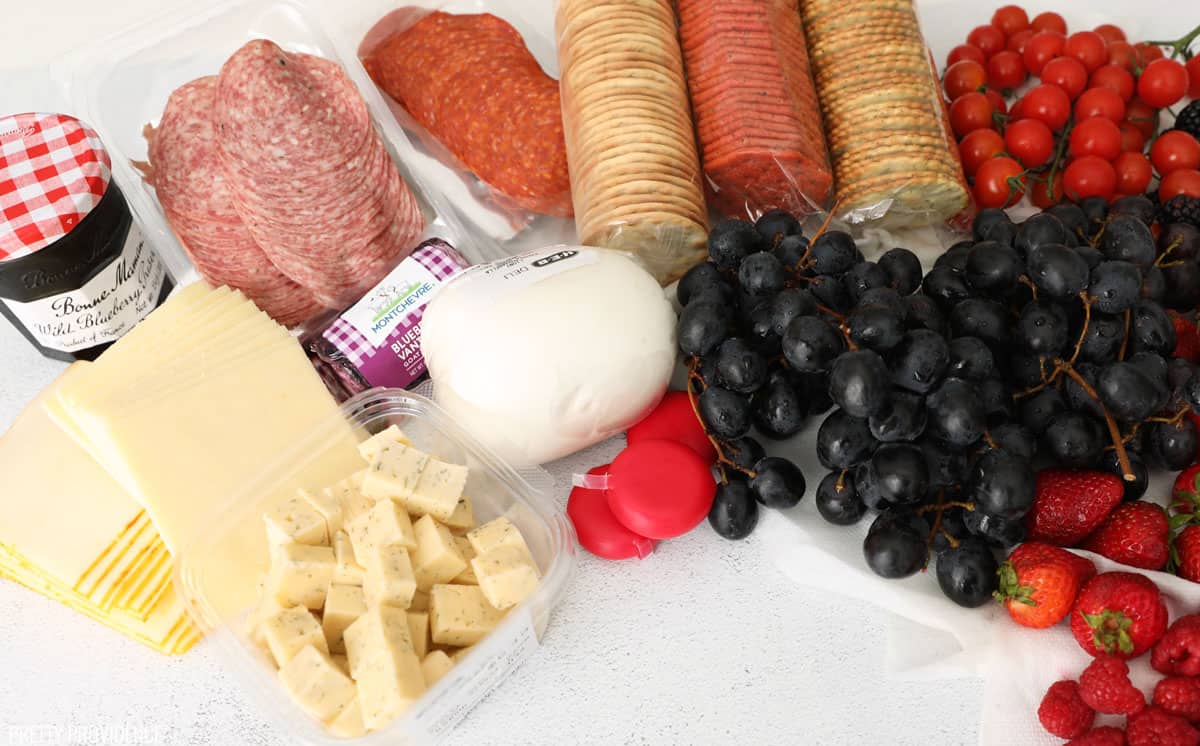 4th of July snacks for a charcuterie board with red, white and blue foods - crackers, meat, cheeses and fruit.