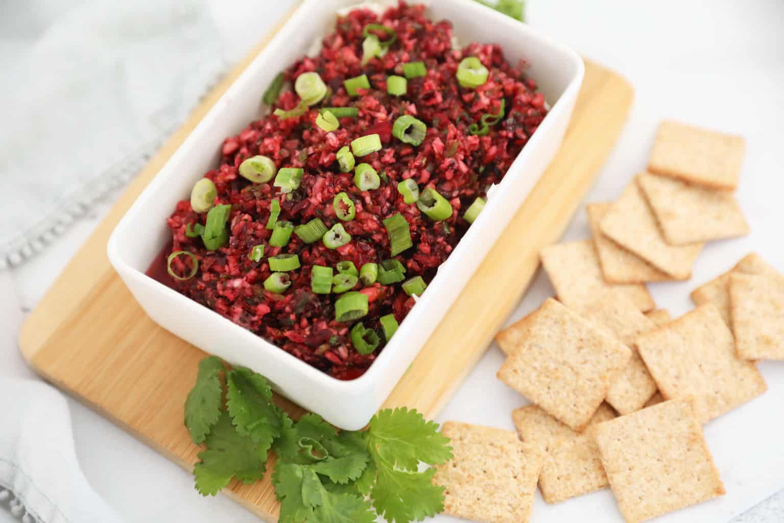 Cranberry Jalapeno dip topped with green onions in a white rectangle dish.