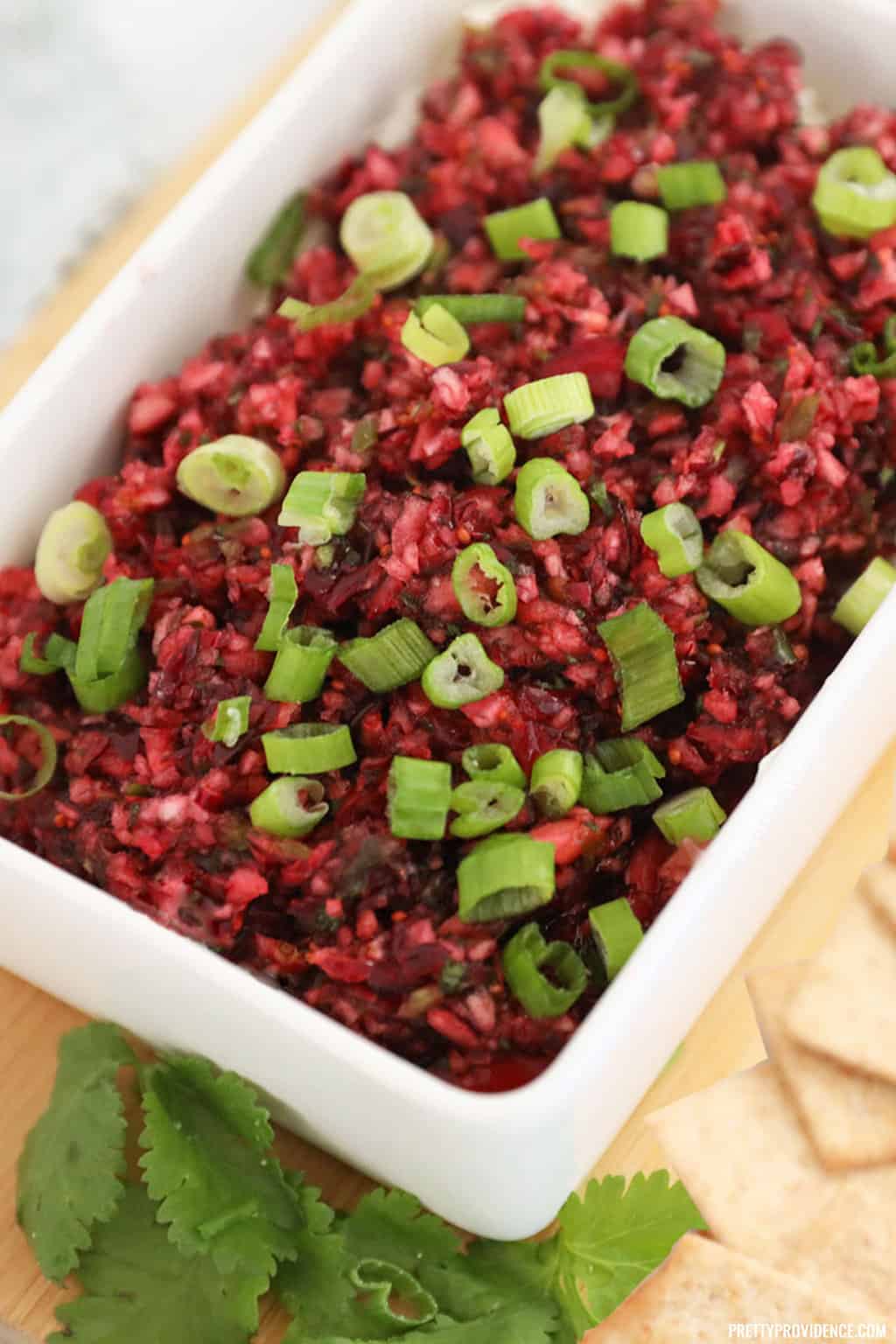 Cranberry Jalapeno dip topped with green onions in a white rectangle dish.