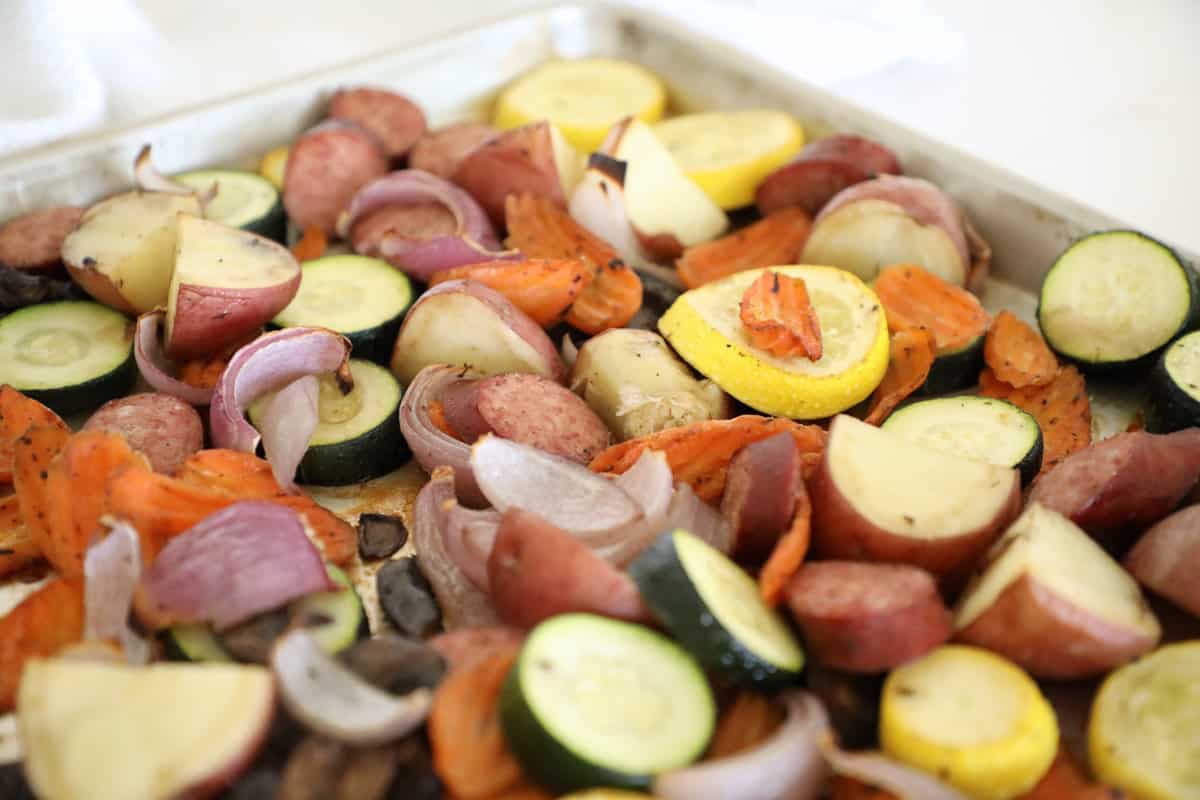 Roasted kielbasa and veggies on a pan. 