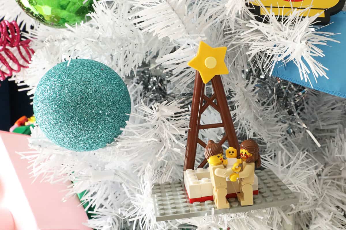 Lego Christmas ornament a nativity scene made out of legos hanging on a white Christmas tree.