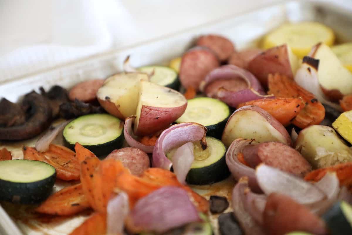 Roasted kielbasa and vegetables on a sheet pan.