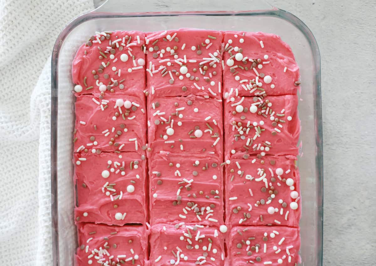 Birds Eye view of a pan of pink frosted sugar cookie bars cut into squares.
