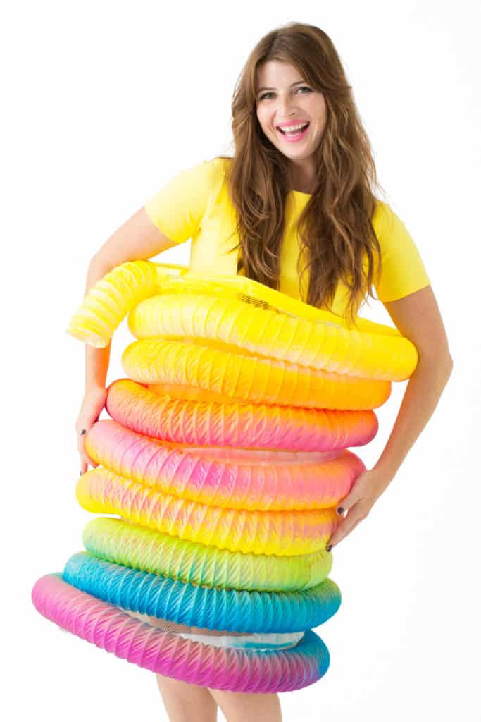 DIY Halloween costume Slinky with rainbow colors on a woman wearing a yellow t-shirt.