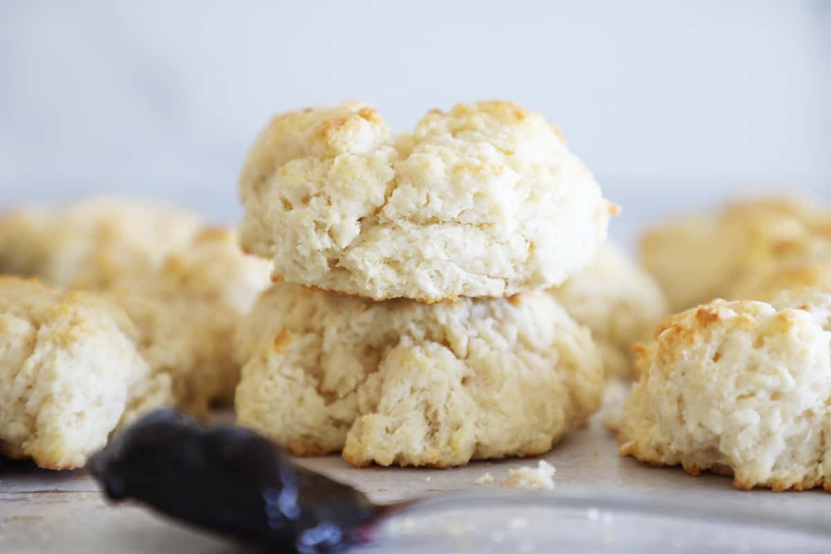 Homemade biscuits in a stack with a spoonful of jam in front of them. 