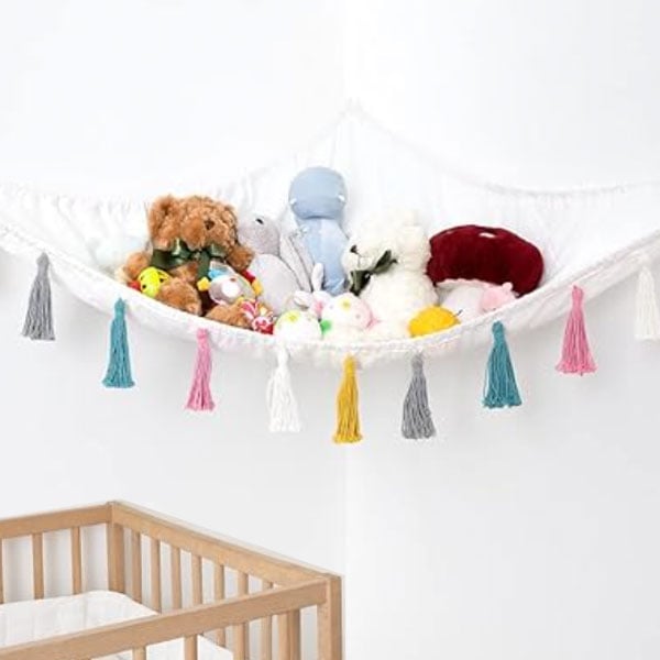 stuffed animals in a hammock with colorful tassels over a crib.