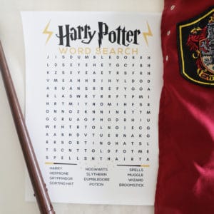 An image of a Harry Potter word search next to a wand and a griffindor cloak.