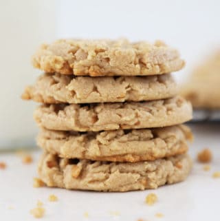 A stack of five old fashioned peanut butter cookies with a jug of milk in the background.