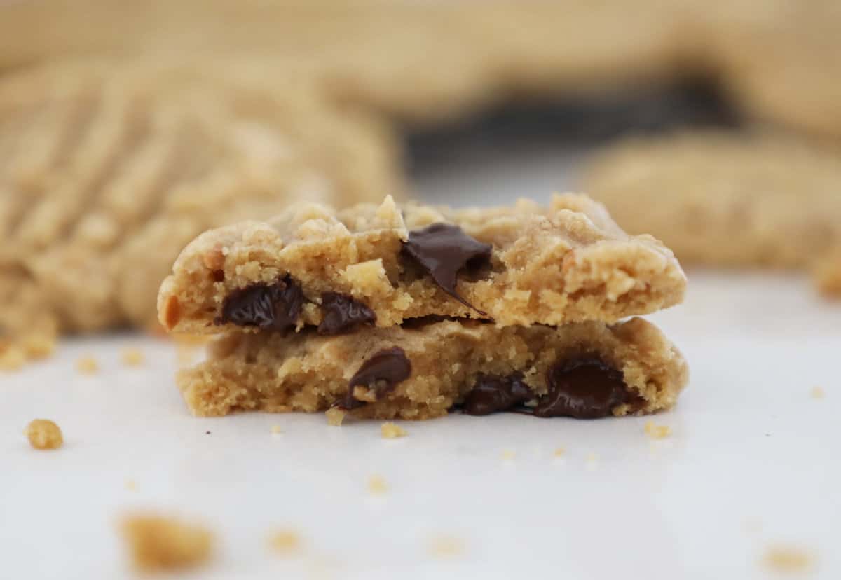 Two halves of a peanut butter cookie with chocolate chips stacked on top of each other.