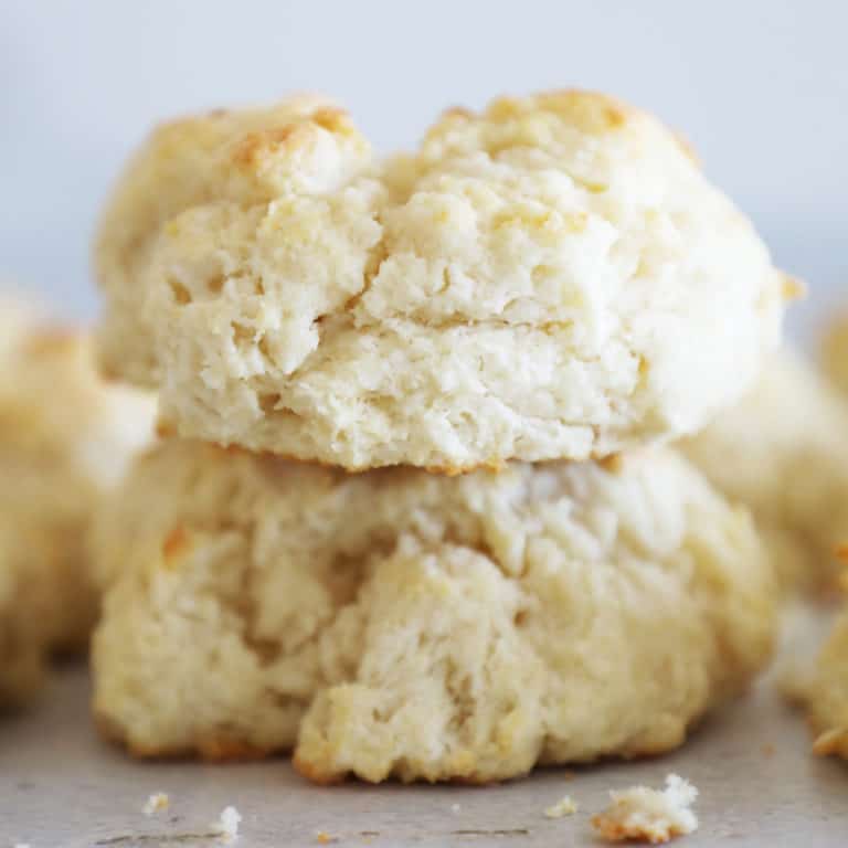 Close up of two homemade biscuits in a stack with some crumbs surrounding.