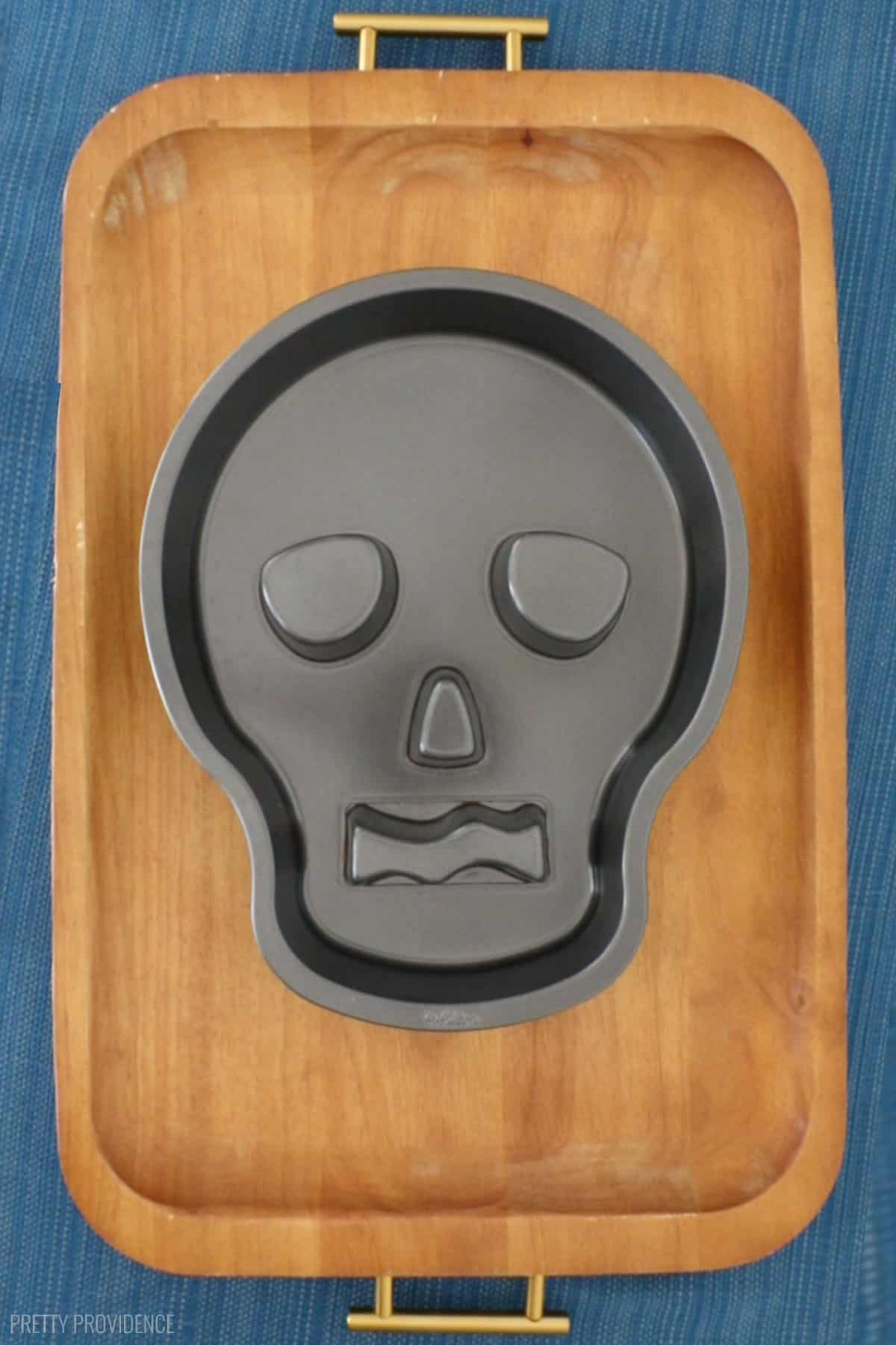 Skull cake pan on a wood charcuterie serving board.