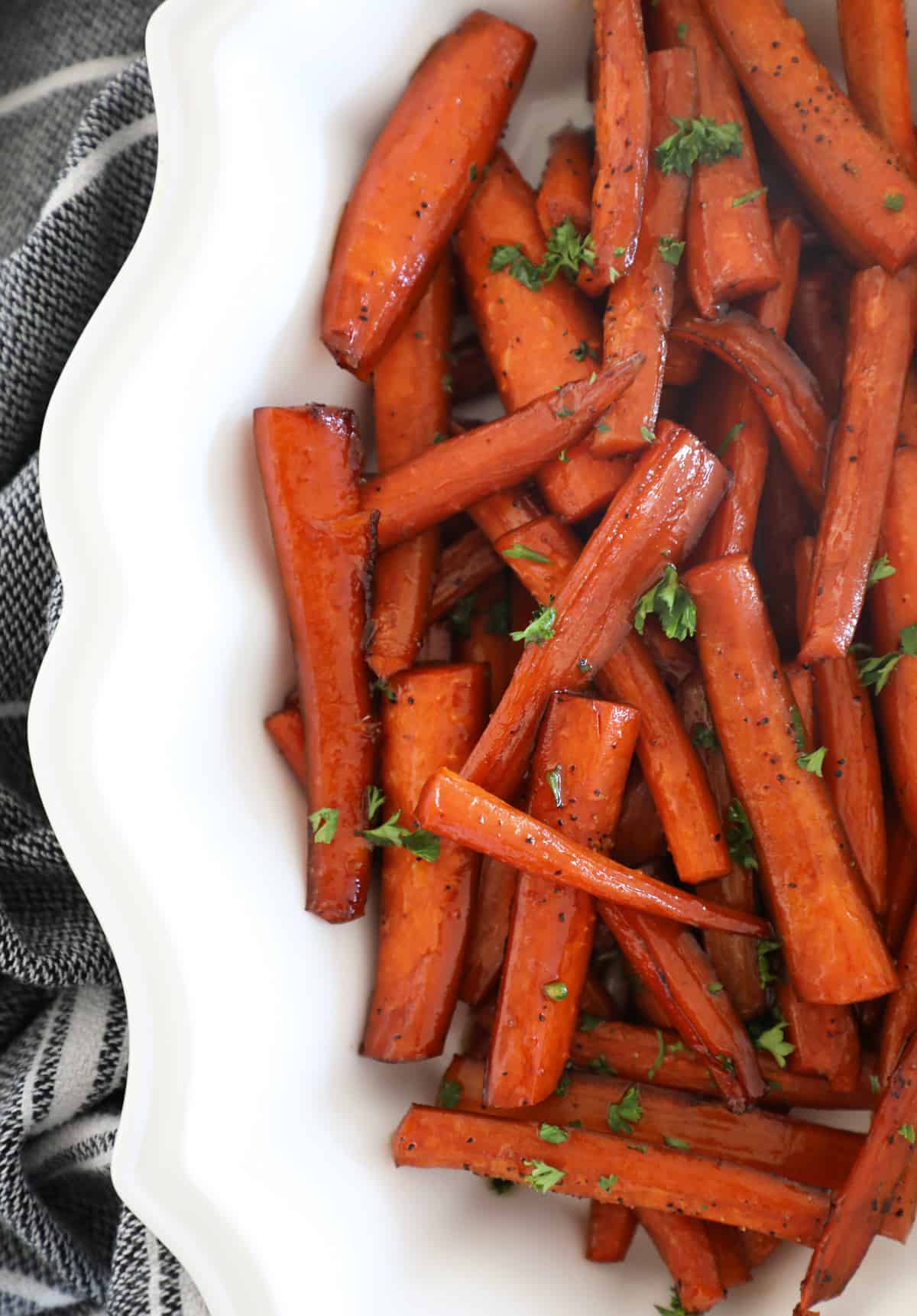 Close up view of a white bowl filled with balsamic glazed carrots. 