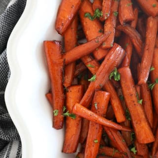 Close up bird's eye view of balsamic roasted carrots in a fancy white bowl.