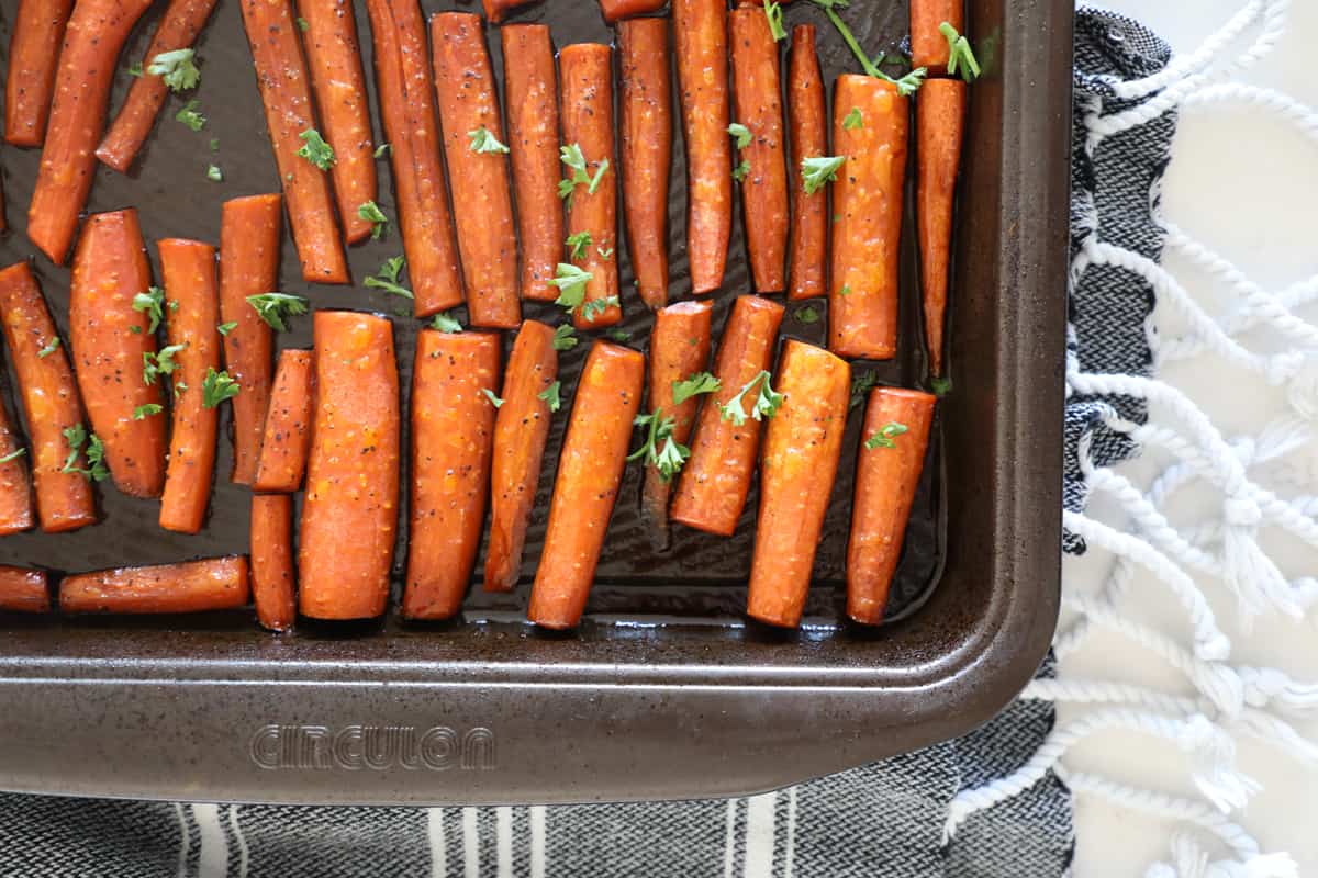 A dark sheet ban lined with carrots for roasting. 