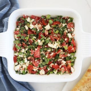 A white 8x8 dish filled with a tomato and feta based bruschetta dip.