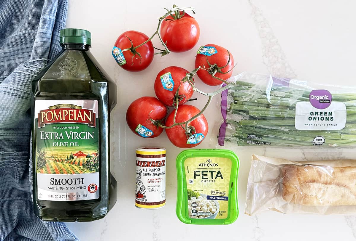 All the ingredients to make feta bruschetta dip lying on a kitchen countertop. 