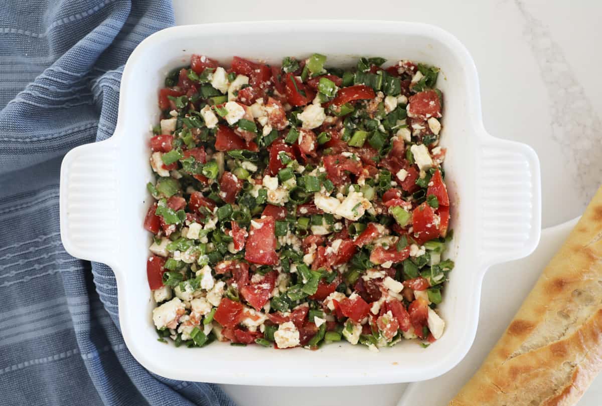 A bird's eye view of a bruschetta dip made from feta, tomatoes and green onions.