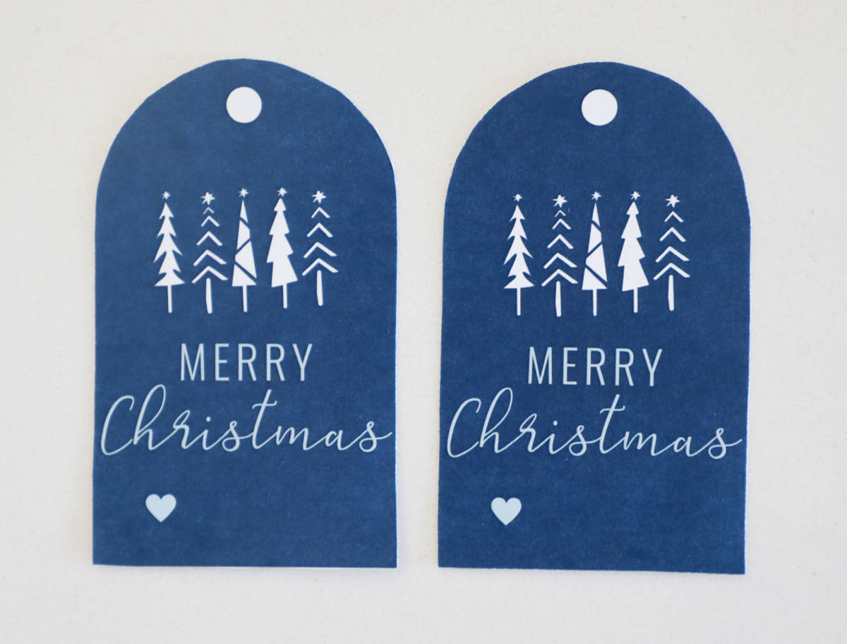 Two printable Christmas tags on a white countertop. 