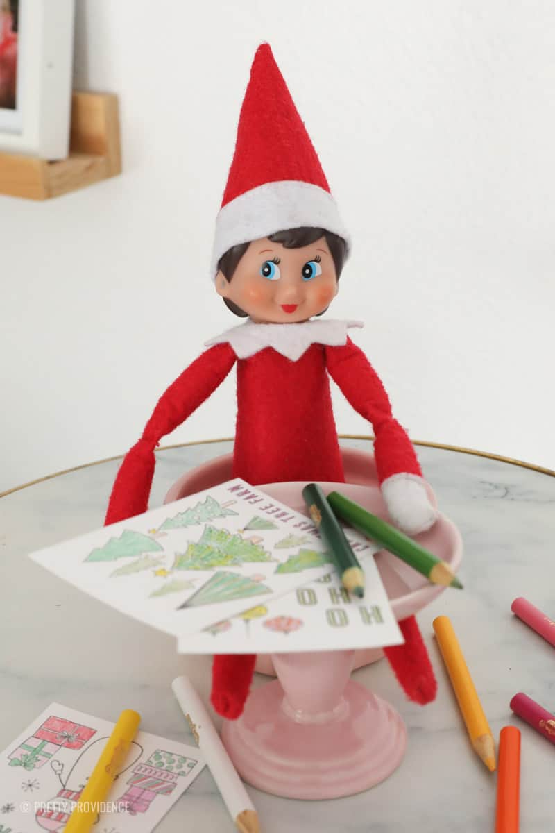 Elf on a shelf coloring some small christmas coloring sheets with mini colored pencils.
