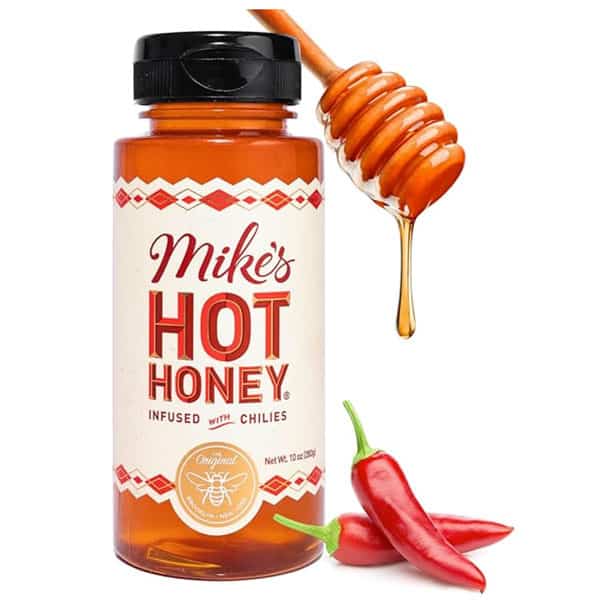 Mike's Hot Honey bottle with a honey wand hanging over it and chili peppers next to it.