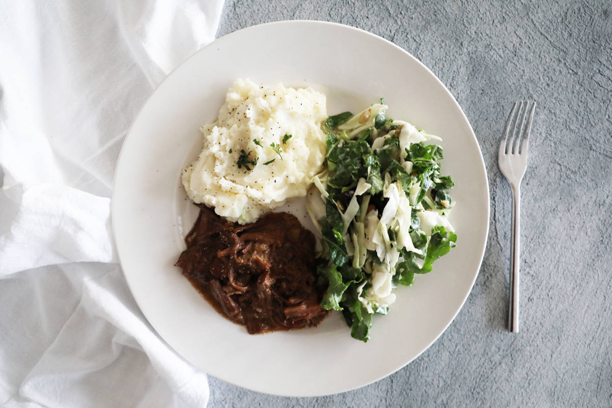 A white plate with pot roast, mashed potatoes and salad. 