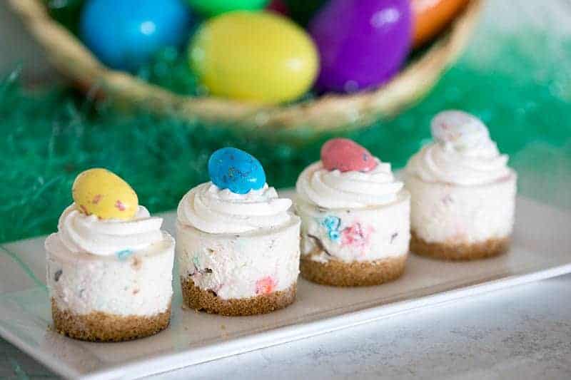 Cute no bake Easter cheesecakes in a line on a small white plate.