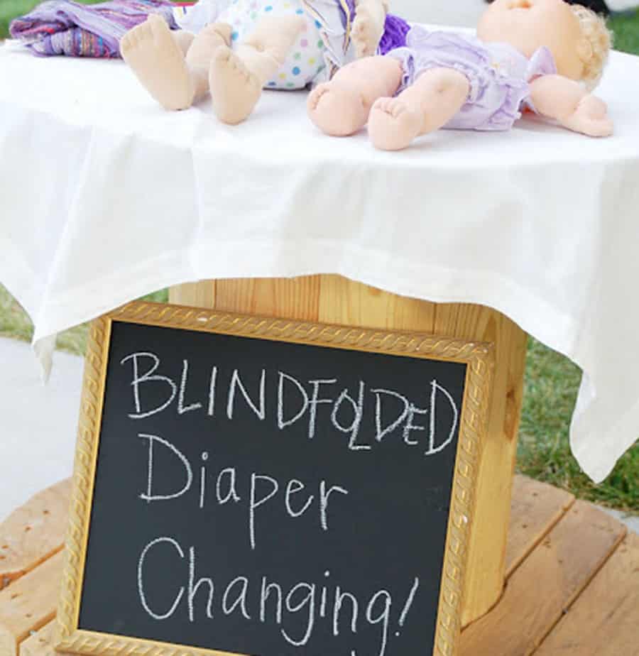 cabbage patch dolls on a table with a sign that says 'blindfolded diaper changing.'