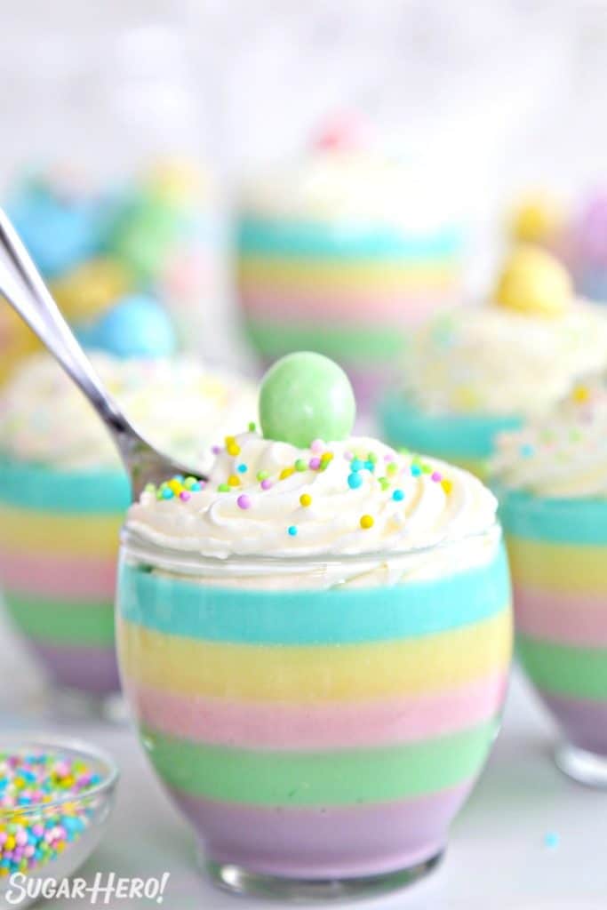 A pastel rainbow gelatin cup with a spoon in it.