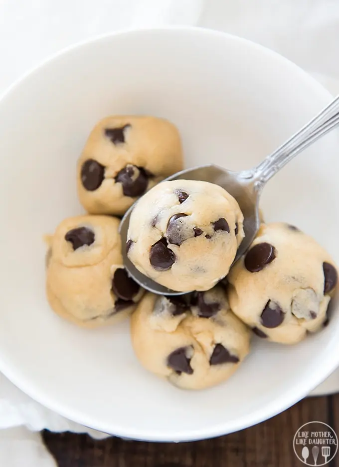 Eggless cookie dough for one, balls of chocolate chip dough in a bowl with a spoon. edible cookie dough that you can safely eat without risk.