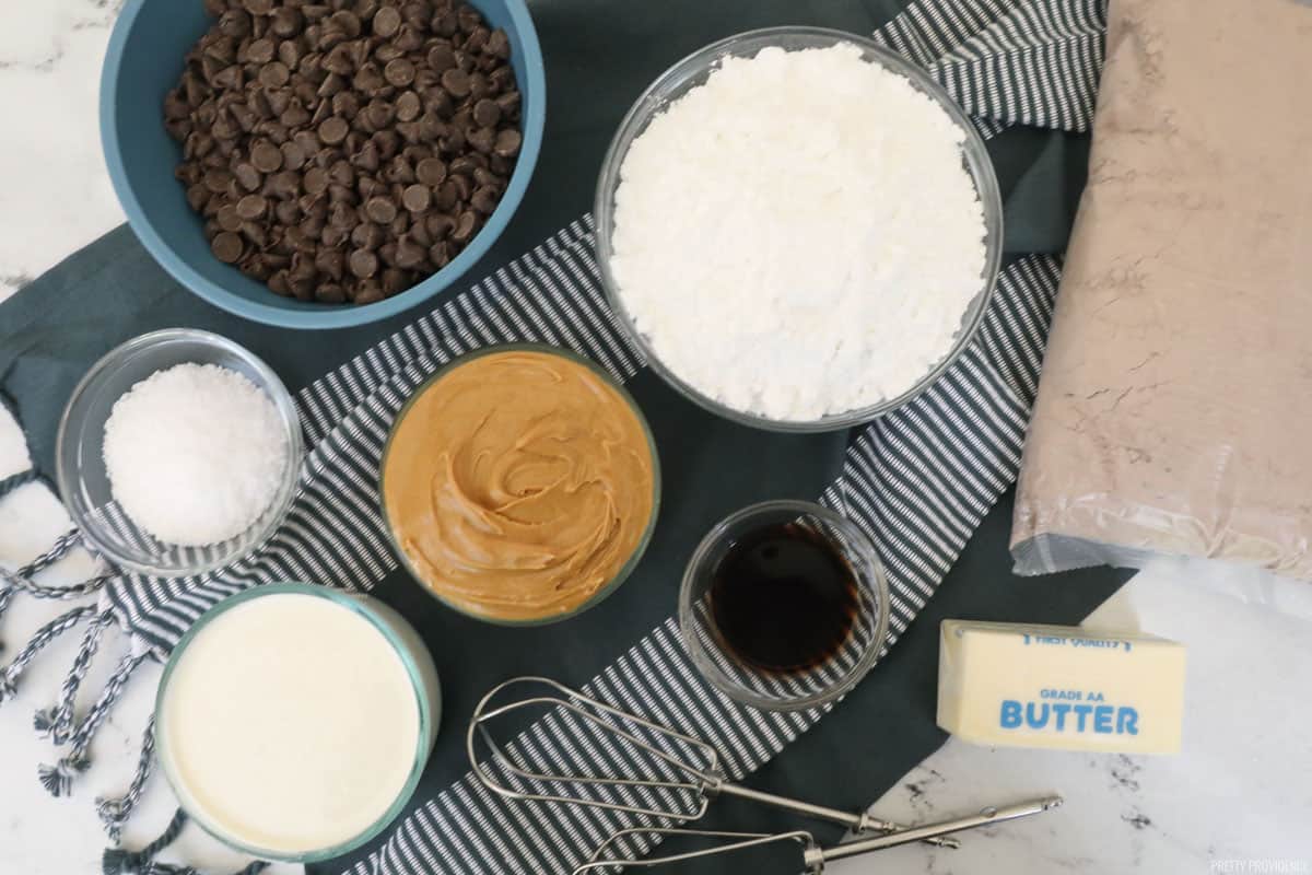 Buckeye brownie ingredients in small bowls: chocolate chips, peanut butter, powdered sugar, vanilla, salt, butter, heavy cream.