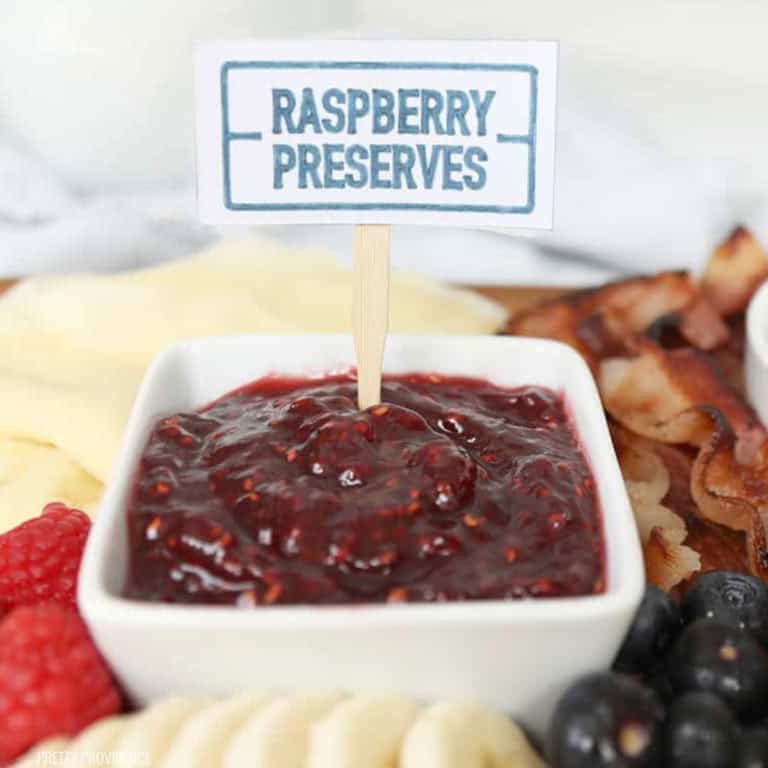 Small white cup with raspberry preserves and labeled with white food labels and made with cricut.