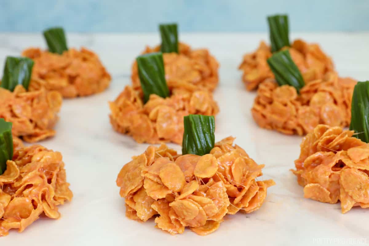 pumpkin cornflake and melted marshmallow treats topped with a green licorice stem.