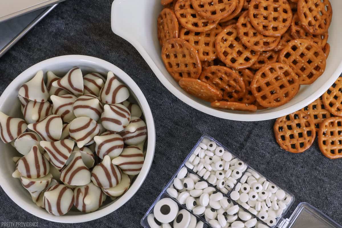 small bowls holding pretzels, hershey's hugs and candy eyeballs resting on a black runnner.