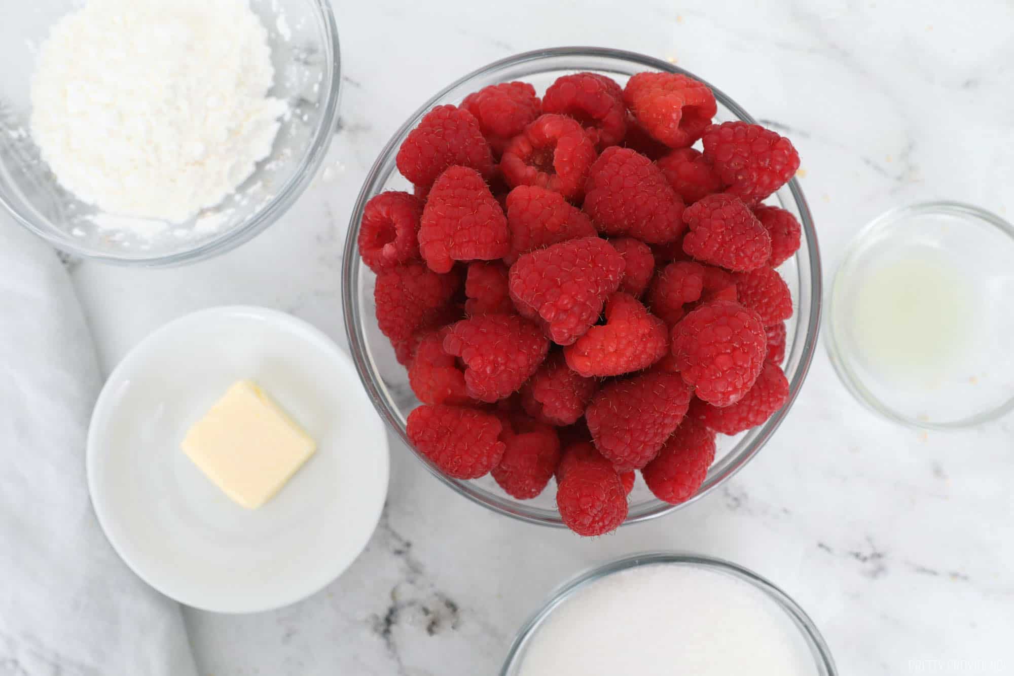 Small bowls with raspberries, powdered sugar, lemon juice, butter, and flour. 