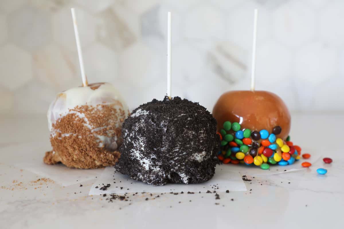 Horizontal photo of three gourmet Carmel apples on a kitchen counter. 