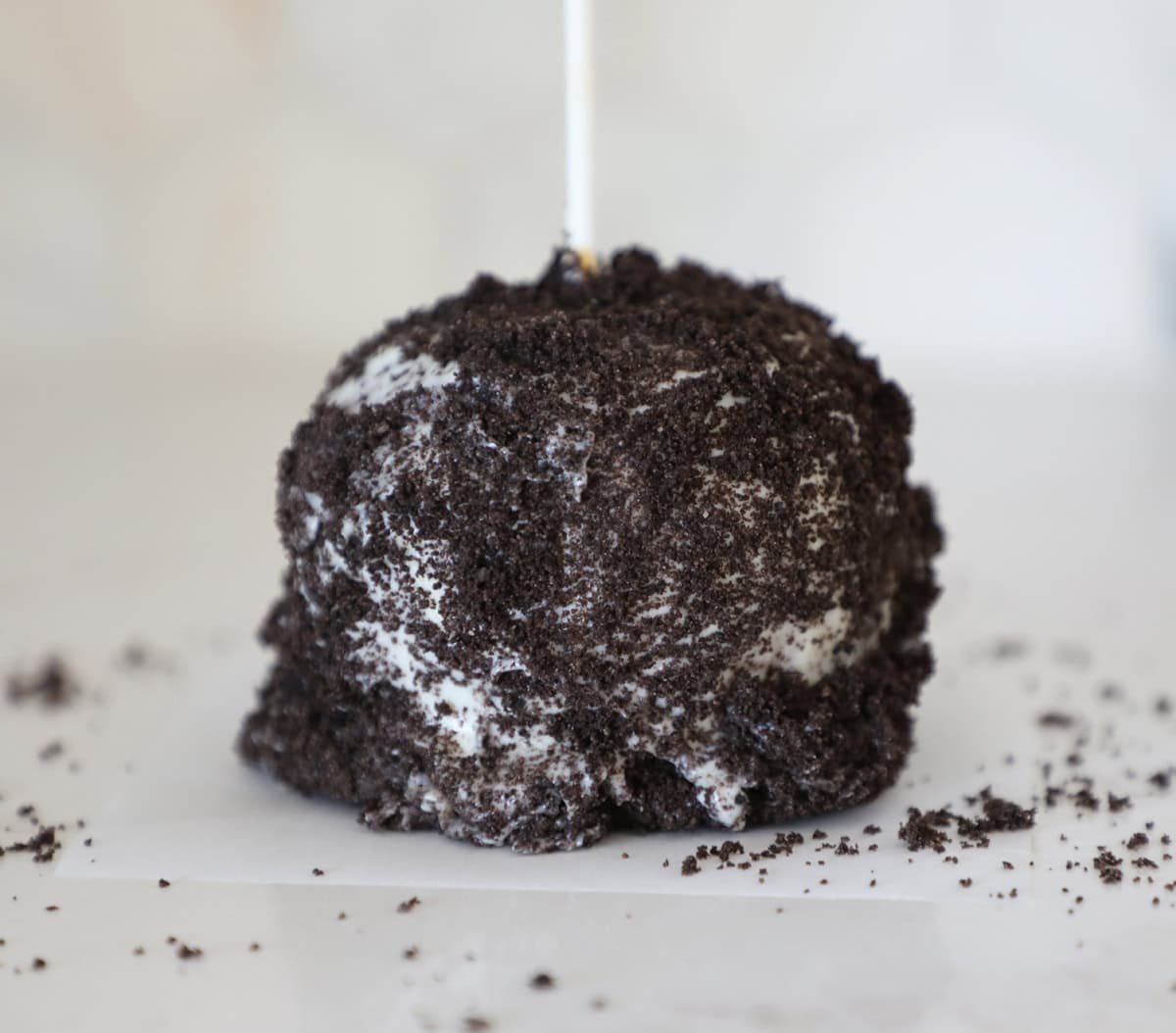 A close up shot of an Oreo flavored homemade caramel apple. 