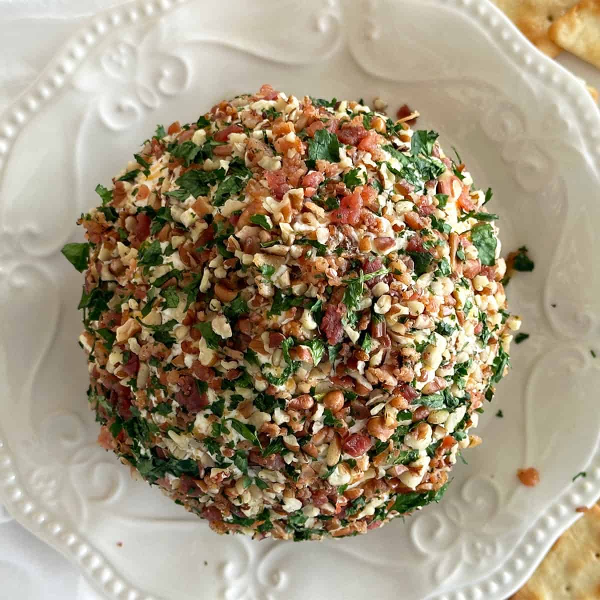 A bird's eye view of a Christmas Cheese Ball on a decorative cream plate. 