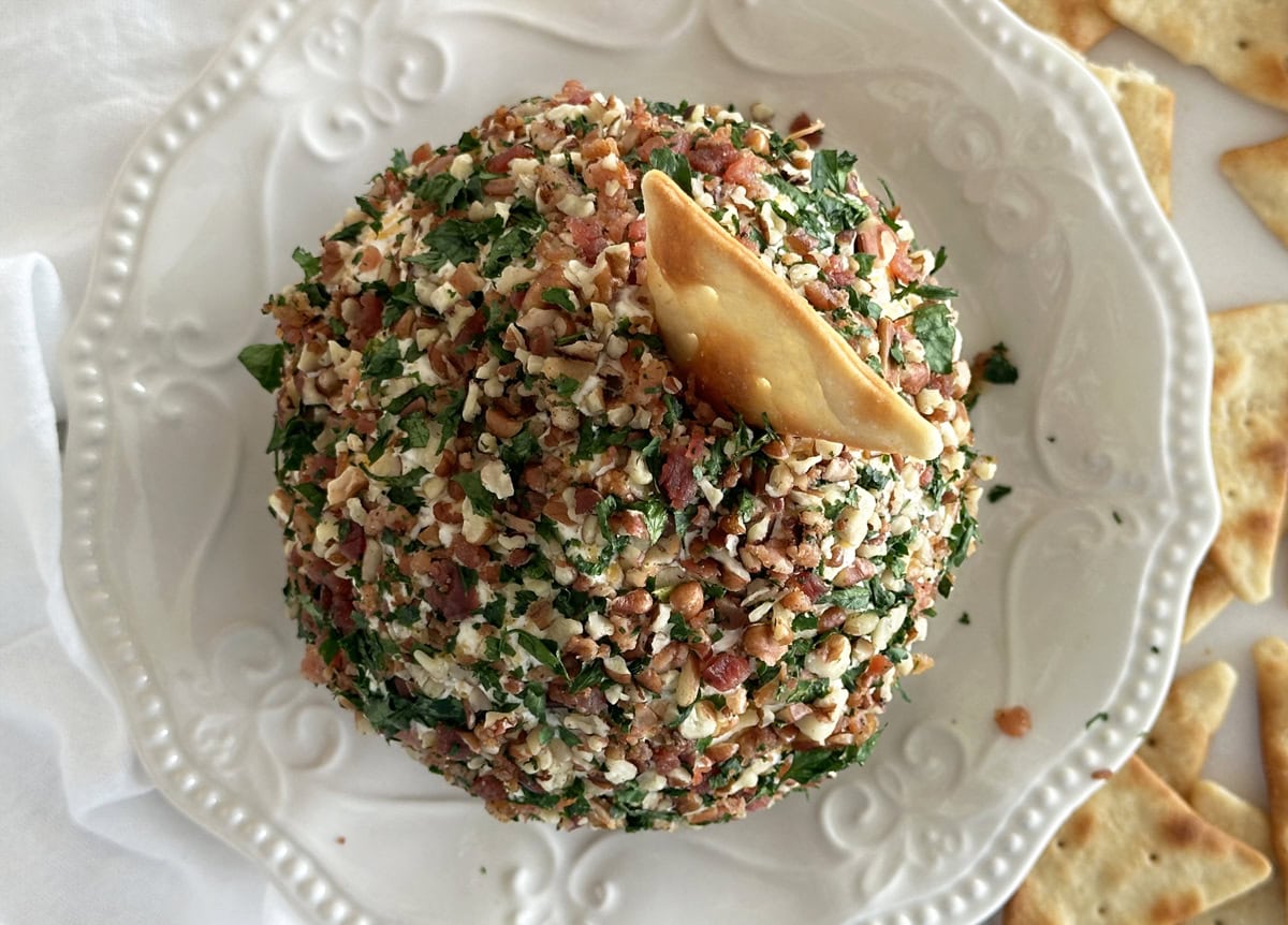 A bird's eye view of a red and green cheese ball with a cracker sticking out the top. 