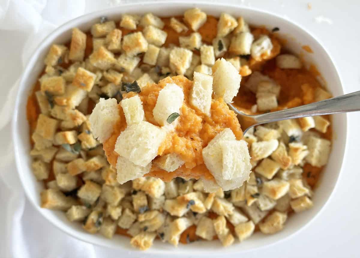 A scoop of savory sweet potato casserole with homemade breadcrumbs. 