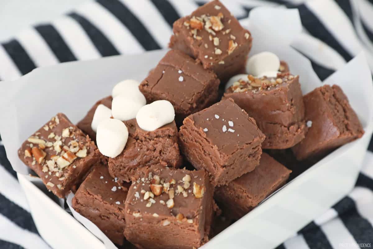 Marshmallow cream fudge cut into small squares, each one topped with pecans, marshmallows or sea salt.