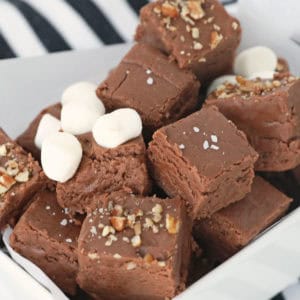 Marshmallow Cream Fudge squares with different toppings - marshmallows, pecans ad sea salt - in a small white dish.